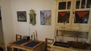 Ein Essbereich mit einem Holztisch, Stühlen, einem Radio und einem Schrank mit Spüle.