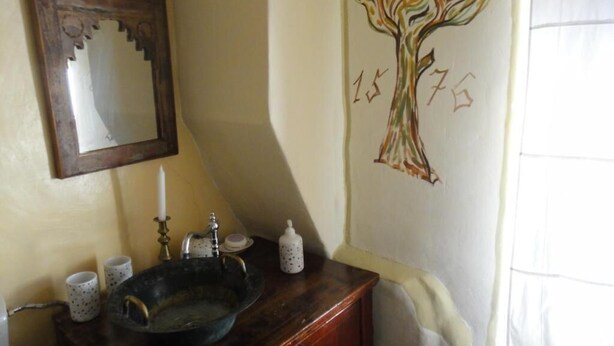Ein Badezimmer mit Waschtisch aus Holz, einem Spiegel, einem Waschbecken und einer Baum-Wandmalerei.