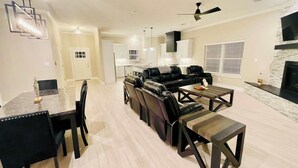 Una sala moderna con un sofá modular, una mesa de comedor con sillas y una chimenea.