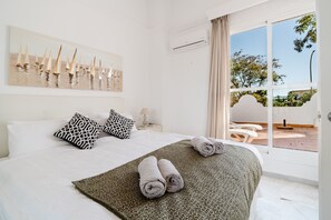 Ein Hotelzimmer mit Bett, einem Bild, einem Fenster und Blick ins Freie.