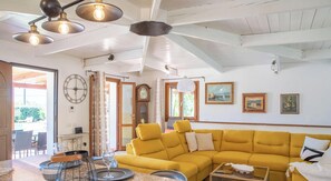 A yellow sofa, a dining table with chairs, a clock, and a window with curtains. - Villa Serena - Alghero (Alghero)