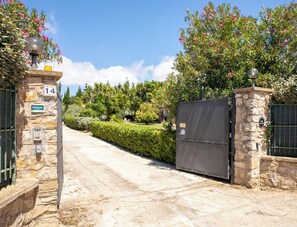 A gated entrance with a stone wall, a number sign, and a villa name sign. - Villa Serena - Alghero (Alghero)