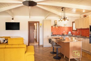 A modern kitchen with a wooden ceiling, a bright orange backsplash, and a central island with bar stools. - Villa Serena - Alghero (Alghero)