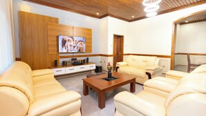 A modern living room with a wooden ceiling, a flat-screen TV mounted on a wooden panel, and a beige sofa set. - Fabulous 4BDR villa with a jacuzzi in exciting Kigali Kimironko for your getaway (Kigali)