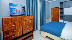 A bedroom with a bed, a wooden dresser, a television, and a wardrobe. - Fabulous 4BDR villa with a jacuzzi in exciting Kigali Kimironko for your getaway (Kigali)