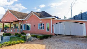 A two-story house with a covered porch, a garage, and a well-maintained garden. - Fabulous 4BDR villa with a jacuzzi in exciting Kigali Kimironko for your getaway (Kigali)