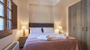 A hotel room with a bed, bedside lamps, a wardrobe, and a radiator. - Porto Santo Mani 1st Apartment (Mani)