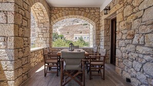 A stone-walled outdoor dining area with a view of a hillside. - Porto Santo Mani 1st Apartment (Mani)