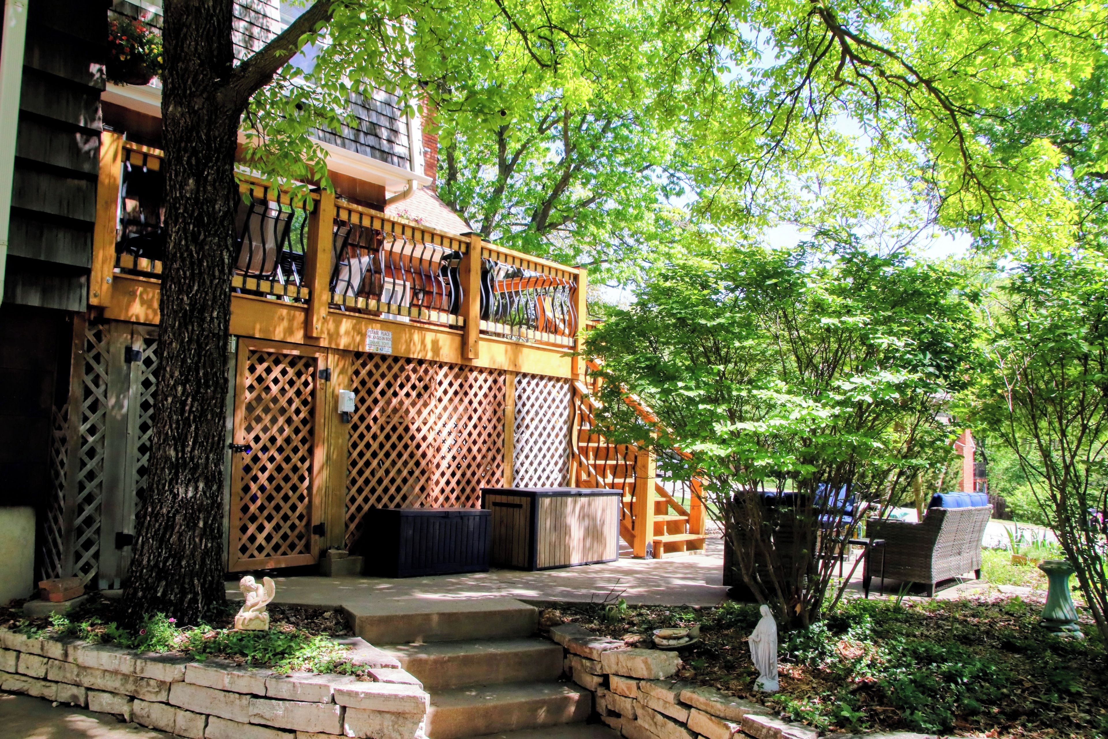 A wooden balcony with a lattice design, a stone bench, and a statue.