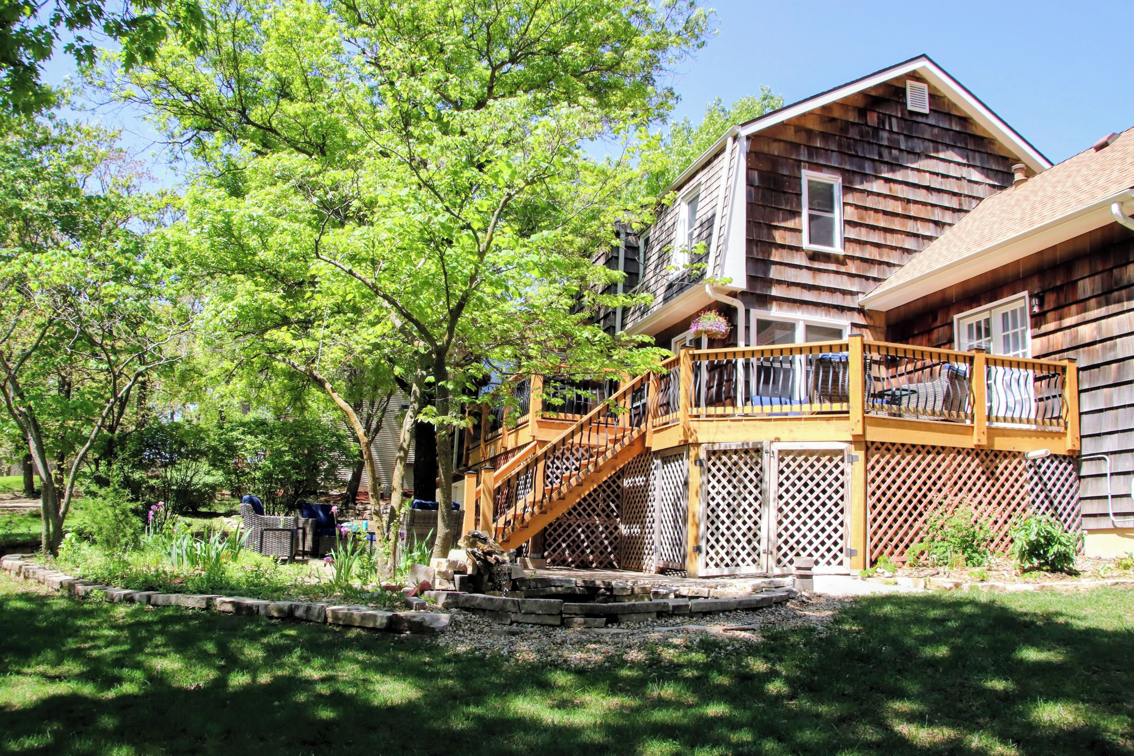 A wooden house with a wooden staircase leading to a deck.