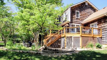 A wooden house with a wooden staircase leading to a deck.