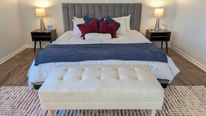 A neatly made bed with a tufted headboard, a matching bench, and two bedside tables with lamps.