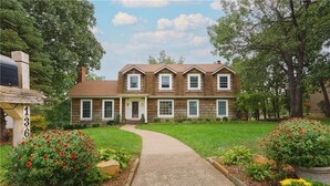 A two-story house with a front porch, a driveway, and a well-maintained lawn.
