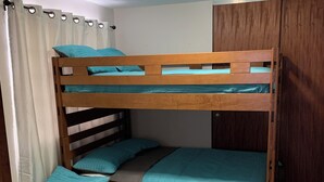 Ein Schlafraum mit zwei Etagenbetten, einem Holzschrank und einer Deckenleuchte.