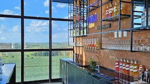 A bar area with a large window, shelves with gin bottles, and a counter with a wooden tray.