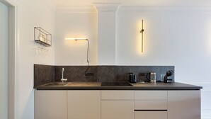 A modern kitchen with a dark countertop, white cabinets, and a built-in sink. - Sense Rooms - Joy (Baveno)