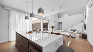 Una cocina moderna con una isla central, armarios de madera e iluminación colgante.