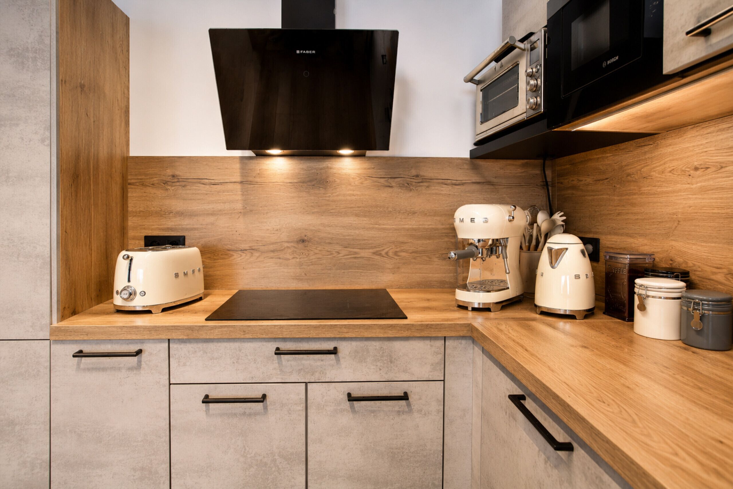 A modern kitchen with a wooden countertop, a toaster, a coffee maker, and a microwave.