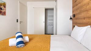 Ein Hotelzimmer mit einem Bett, einem hölzernen Kopfteil, einer weißen Tür und einem Flur, der zu einem Badezimmer führt.