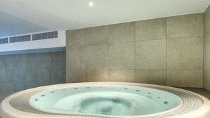 Ein Whirlpool in einem modernen Badezimmer mit gefliesten Wänden und einem Dachventilator.