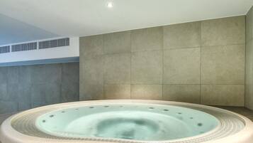 Een whirlpool in een moderne badkamer met betegelde wanden en een dakraam.