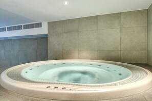 A hot tub in a modern bathroom with tiled walls and a ceiling vent. - Apartment Aiguille d'Or (Les Houches)