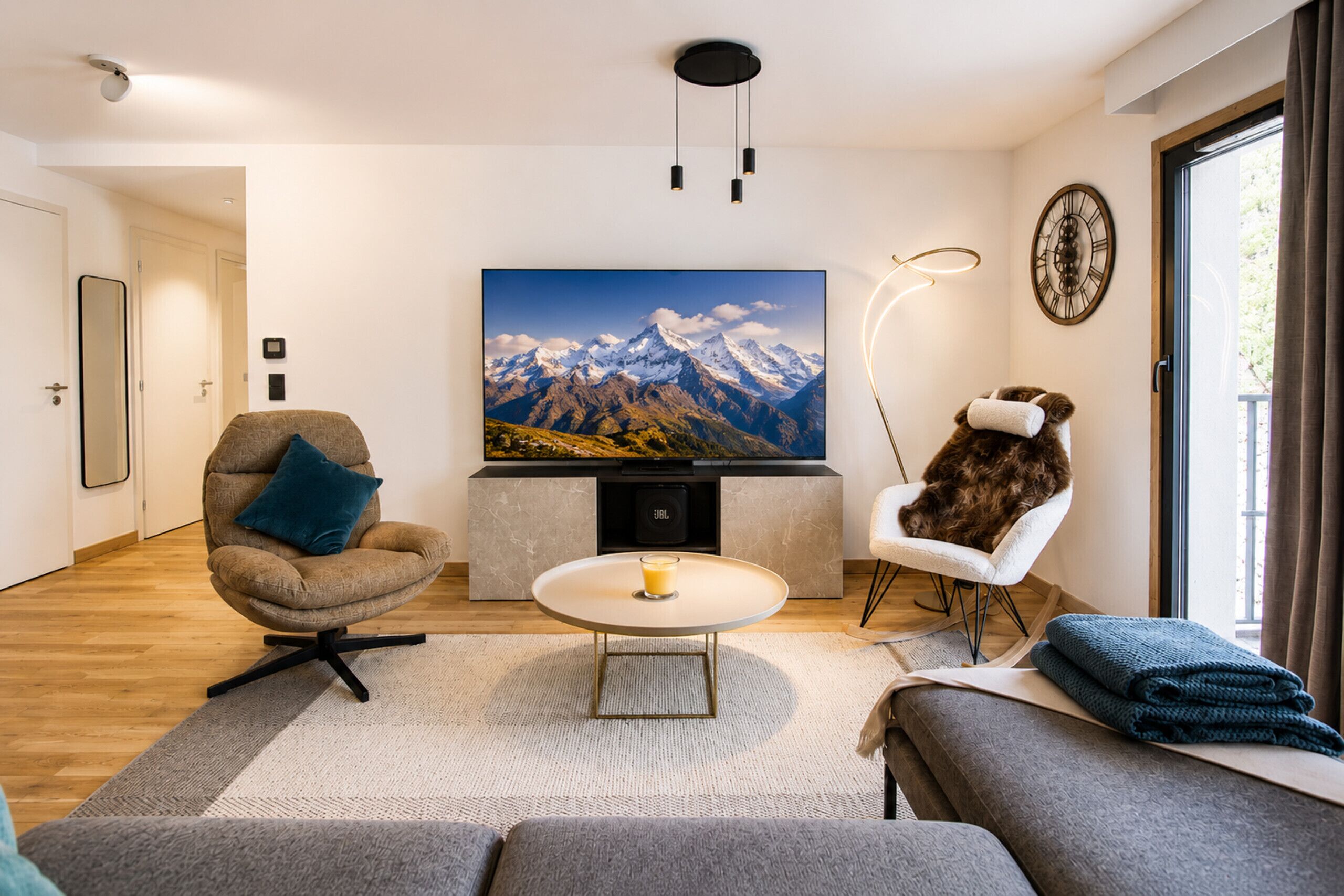 Un salon moderne avec un téléviseur à écran plat, un canapé, un fauteuil et une table basse.