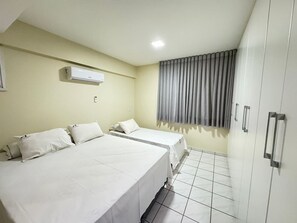 A hotel room with two beds, a wardrobe, a window with curtains, and an air conditioning unit. - Aquarius Residence (Caldas Novas)