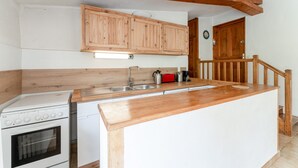 Une cuisine avec des meubles de rangement en bois, une cuisinière, un évier et un îlot central en bois.