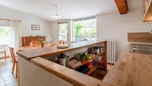 Une cuisine dotée de plans de travail en bois, d’un four encastré, d’un évier et d’une fenêtre donnant sur un paysage verdoyant.