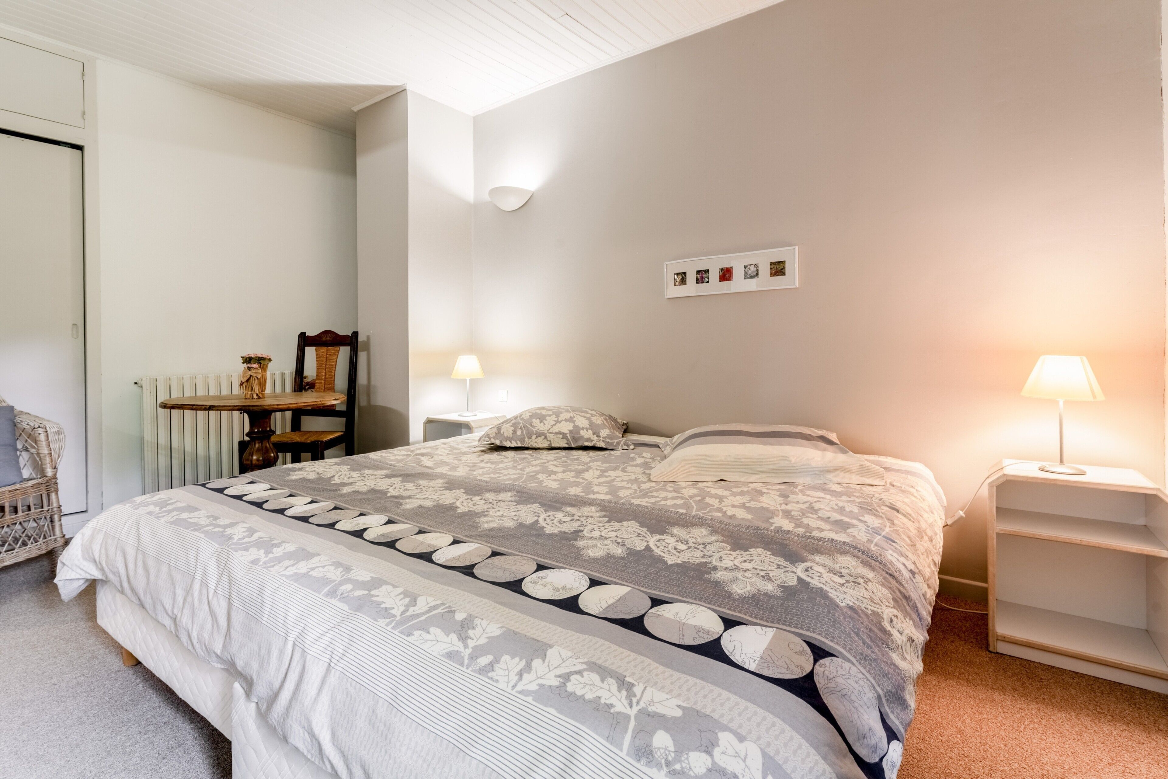 Een slaapkamer met een groot bed, twee nachtkastjes, een stoel, een radiator en een wandlamp.