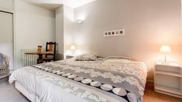 Een slaapkamer met een groot bed, twee nachtkastjes, een stoel, een radiator en een wandlamp.