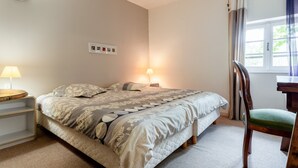Een slaapkamer met een bed, bedlampen, een stoel, een bureau en een raam met gordijnen.