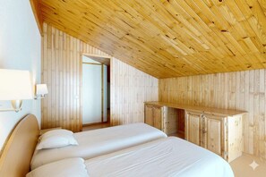 Une chambre avec un plafond en pente, des murs en bois et une armoire intégrée en bois.