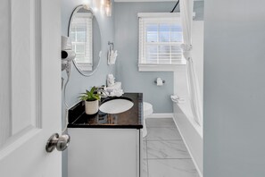 A bathroom with a black countertop, white sink, and a potted plant. - Sea Breeze Retreat (North Myrtle Beach)