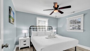A bedroom with a bed, nightstands, a ceiling fan, and windows with blinds. - Sea Breeze Retreat (North Myrtle Beach)