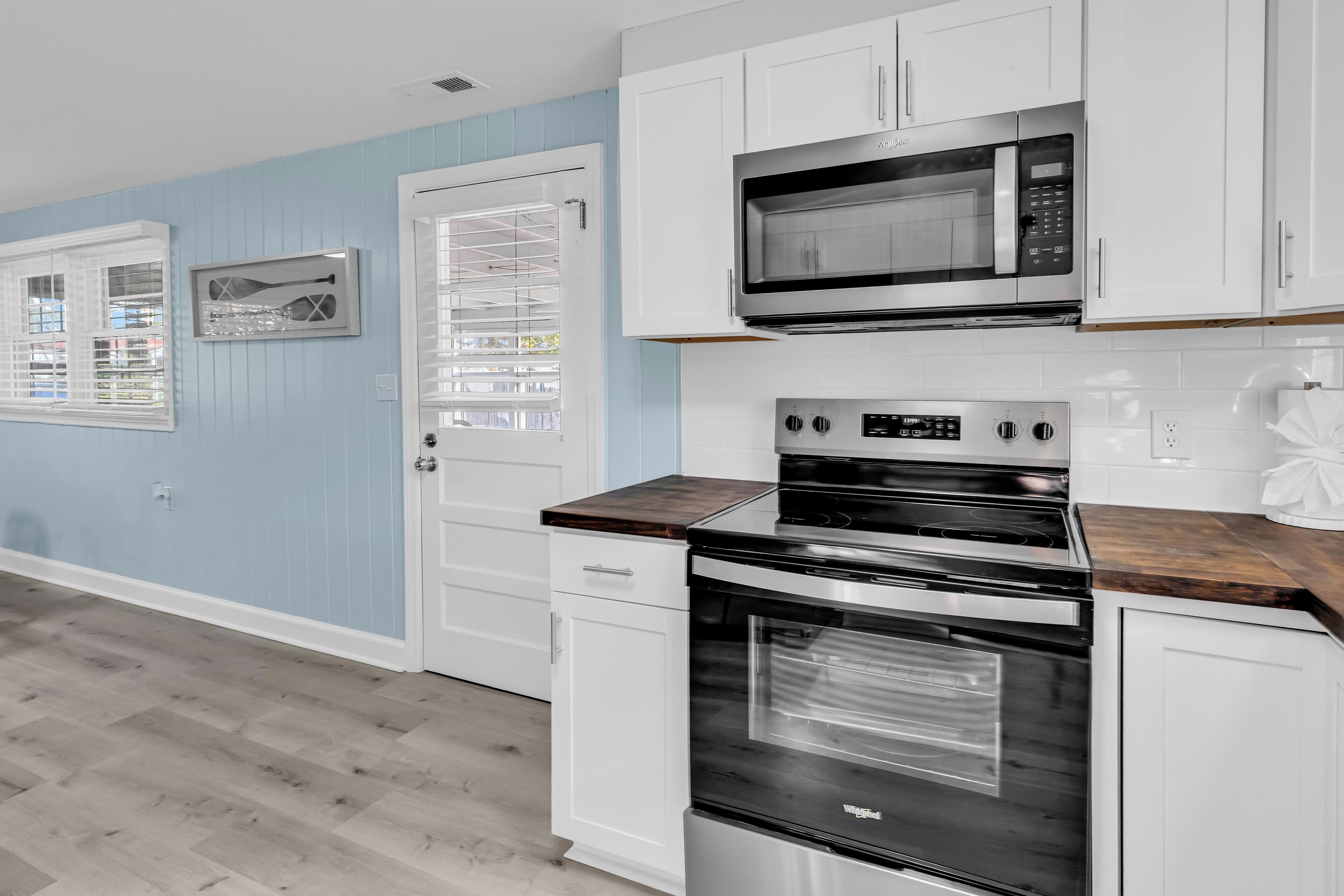 A kitchen with white cabinets, a stainless steel microwave, and a built-in oven.