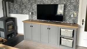 Ein Wohnzimmer mit Kamin, einem Fernseher auf einer Holzhocker und Korbwäschekörben.