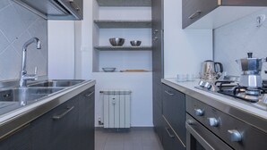 Cozinha moderna com pia de aço inoxidável, fogão embutido e máquina de café.