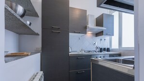 Uma cozinha moderna com armários escuros, uma pia de aço inoxidável e uma janela que proporciona luz natural.