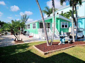 A two-story house with a green exterior, white trim, and a front porch. - Cozy 1-bedroom cottage in gorgeous Jensen Beach gated community (Jensen Beach)