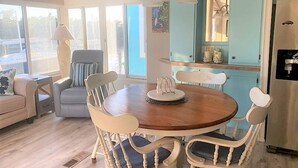 Een eetgedeelte met een ronde houten tafel, witte stoelen en een blauwe kast op de achtergrond.