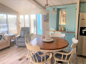 A dining area with a round wooden table, white chairs, and a blue cabinet in the background. - Cozy 1-bedroom cottage in gorgeous Jensen Beach gated community (Jensen Beach)
