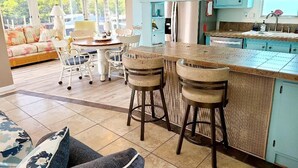 Een moderne keuken met een centraal eiland, barkrukken en een zithoek met een bank en stoelen.