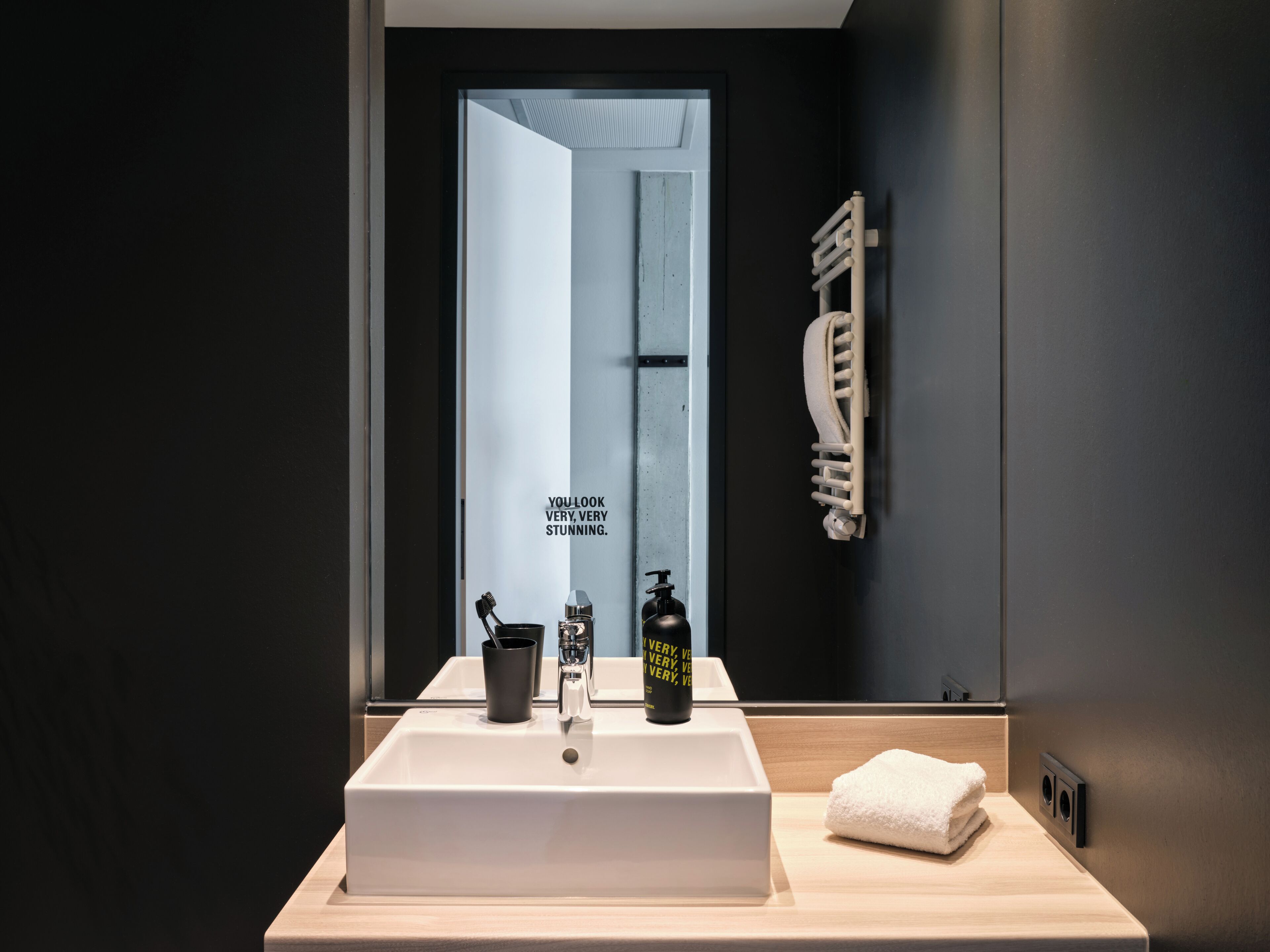 Un baño moderno con un lavamanos blanco, una toalla y un espejo.
