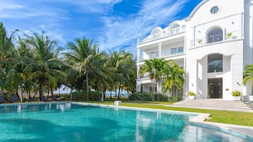 Un grand bâtiment blanc avec une piscine et des palmiers.