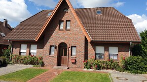 A brick house with a pitched roof, a central entrance with an arch, and a small window above the door. - Apartment 'Am Meer Nordsee' with Shared Garden, Balcony & Wi-Fi (Wangerland)