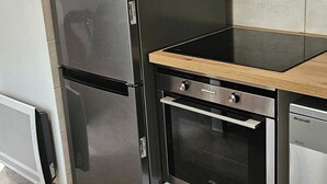 A kitchen with a stainless steel refrigerator, a built-in oven, and a dishwasher. - DETACHED BUNGALOW AT THE BACK OF OUR 2-STAR VILLA (Fréjus)