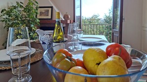 Een eettafel met een schaal fruit, wijnglazen en een fles wijn.