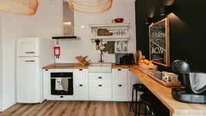 Eine moderne Küche mit weißen Schränken, einer Holz Arbeitsplatte, einem Einbauofen und einer schwarzen Arbeitsplatte mit Kaffeemaschine.